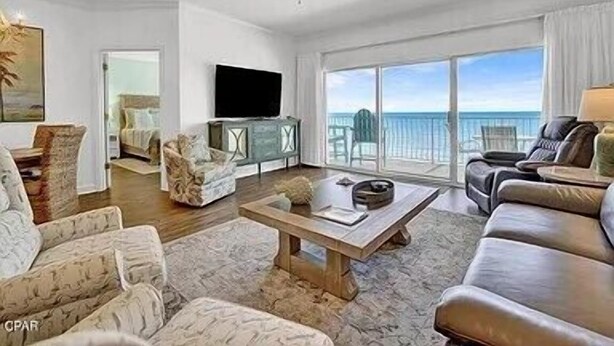A spacious living room with a ceiling fan, a television, and a large window offering a view of the ocean. - Coral Reef Unit #1304 (Beachfront 2 bedroom 2 bath condo on the 13th floor) (Panama City Beach)