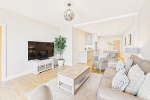 Un salon moderne avec un téléviseur à écran plat, une table basse, un canapé et une plante en pot.