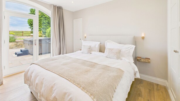 A spacious bedroom with a large bed, a sliding glass door leading to an outdoor area, and a minimalist decor.