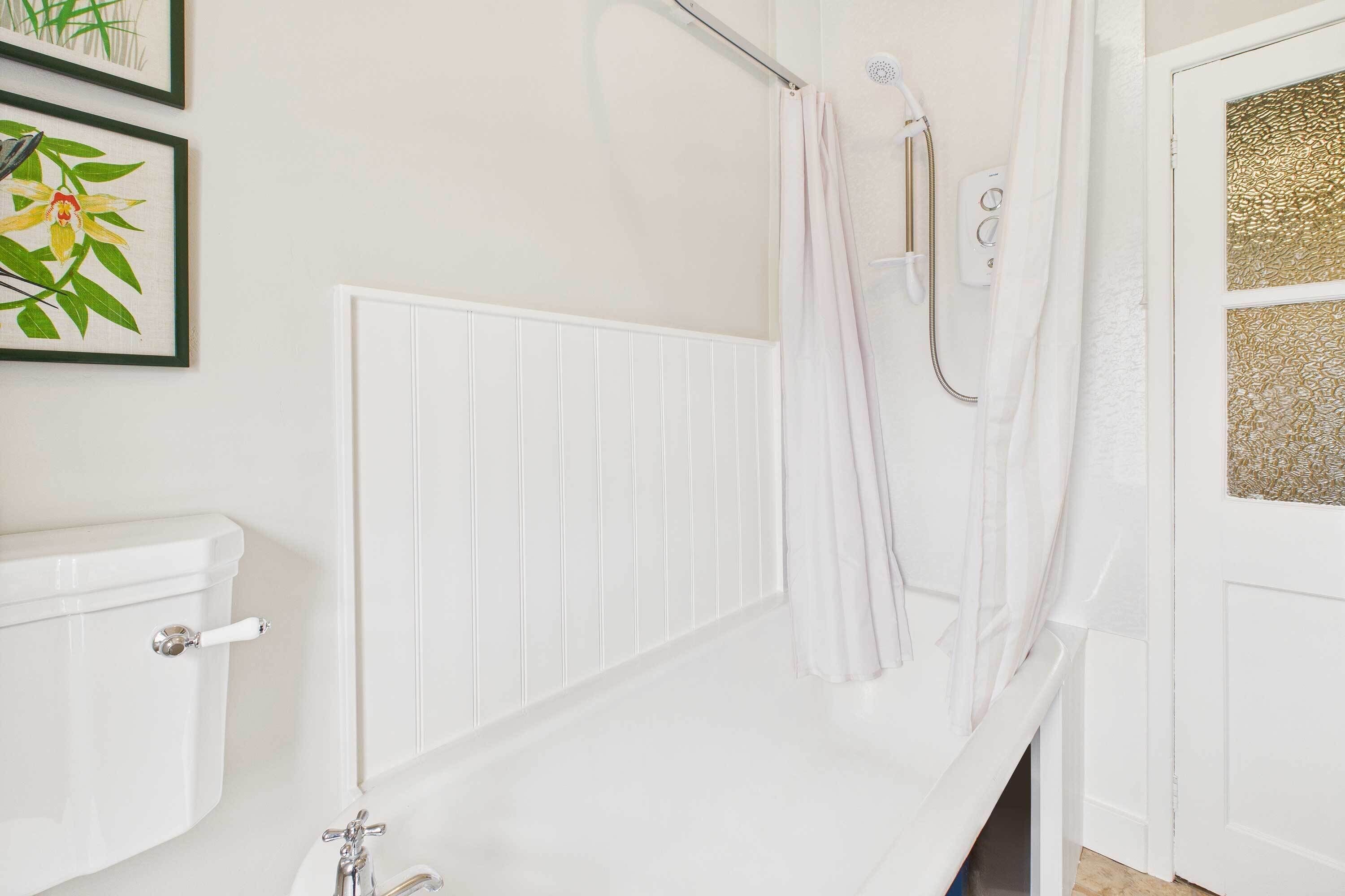 A bathroom with a white toilet, a white bathtub, and a shower with a curtain.