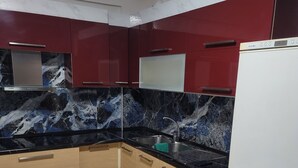 A compact kitchen with a white refrigerator, a black countertop, and wooden cabinets. - Chic 1-bedroom apartment with WiFi, AC in beautiful Durrës near the sea (Durrës)