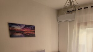 A hotel room with two beds, a painting on the wall, an air conditioning unit, and a window with curtains. - Chic 1-bedroom apartment with WiFi, AC in beautiful Durrës near the sea (Durrës)