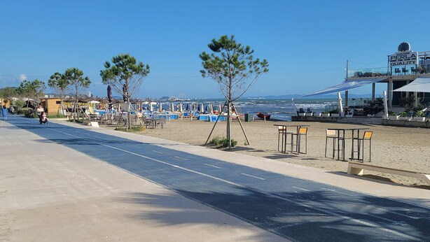 A beachside road with a clear view of the sea, a few trees, and a building with a sign reading "Made in Perla Quality". - Chic 1-bedroom apartment with WiFi, AC in beautiful Durrës near the sea (Durrës)