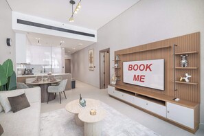 Un salon moderne avec un coin repas, un téléviseur fixé sur un mur en bois et une cuisine en arrière-plan.