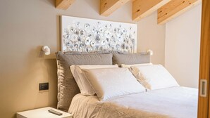 Une chambre à coucher comprenant un lit, une table de chevet et un luminaire fixé au mur.