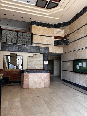 Eine geräumige Lobby mit Empfangsschalter, einer Treppe und einem schwarzen Brett.