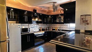 A modern kitchen with black cabinets, stainless steel appliances, and a central island.