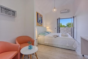 Ein modernes Schlafzimmer mit einem Bett, einem Sessel, einem Tisch und Blick durch ein großes Fenster.