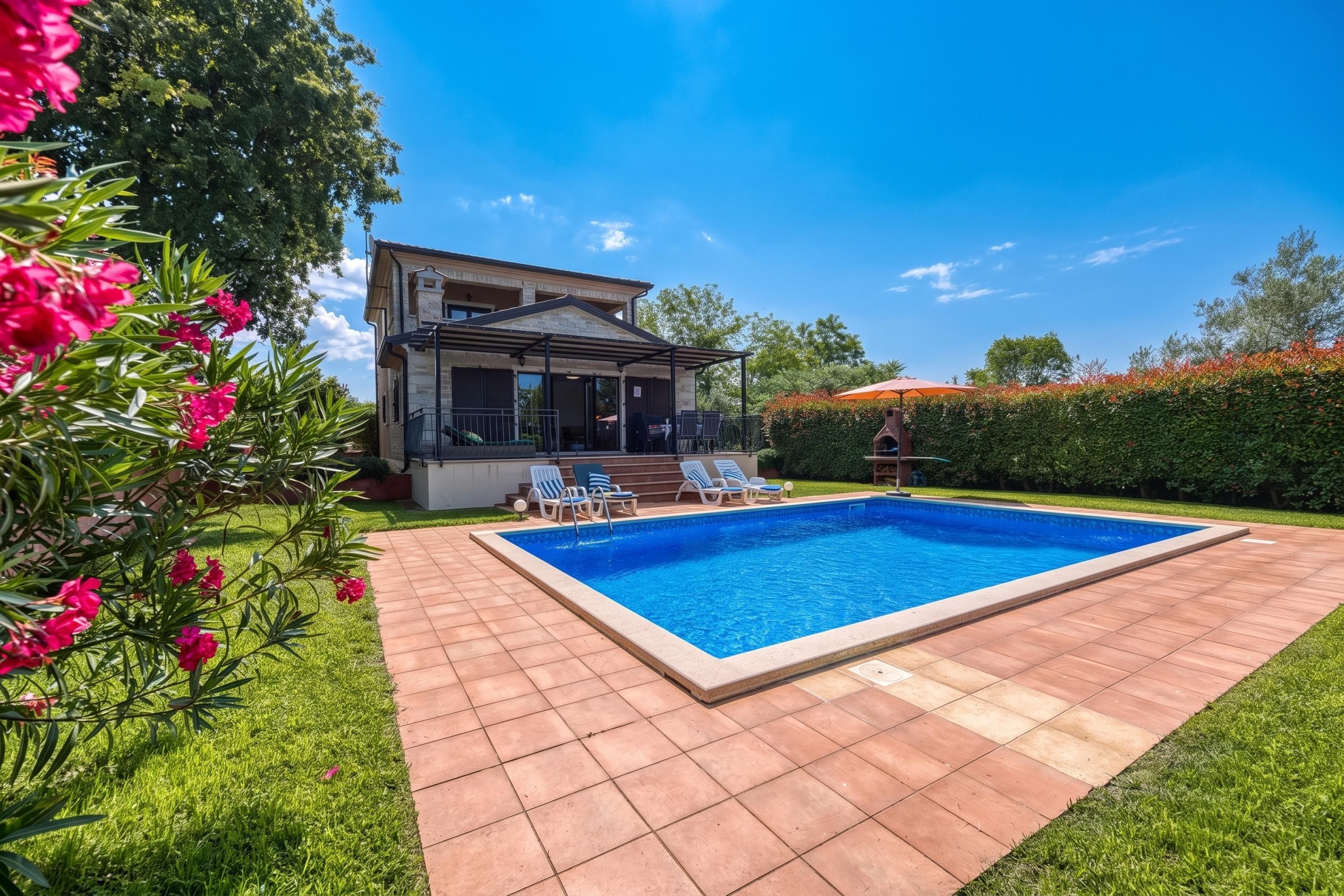 A two-story house with a swimming pool, a covered patio, and a well-maintained garden.