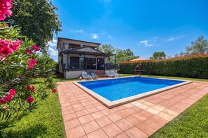Une maison à deux étages dotée d’une piscine, d’un patio couvert et d’un jardin bien entretenu.