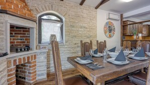 Un coin repas avec une cheminée en briques, une table en bois et des chaises.