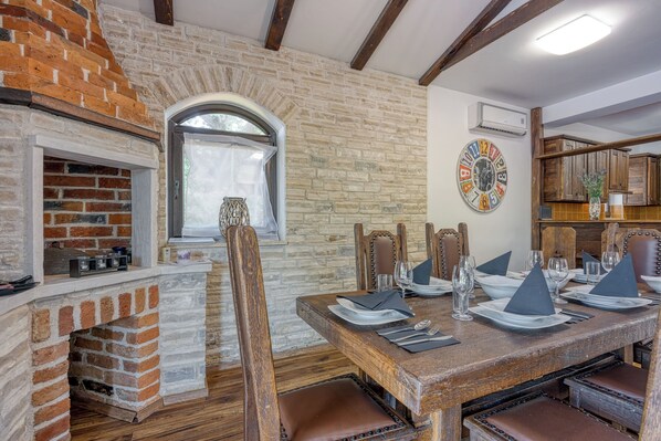 A dining area with a brick fireplace, wooden table, and chairs. - Villa Kristina With Pool (Tar-Vabriga)