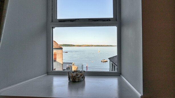 A window with a view of a calm body of water, a boat, and a distant shoreline. - Nor Nour, Cawsand (Cawsand)