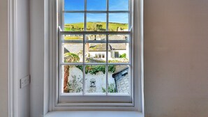 A window with a view of a rural landscape, including fields and buildings.