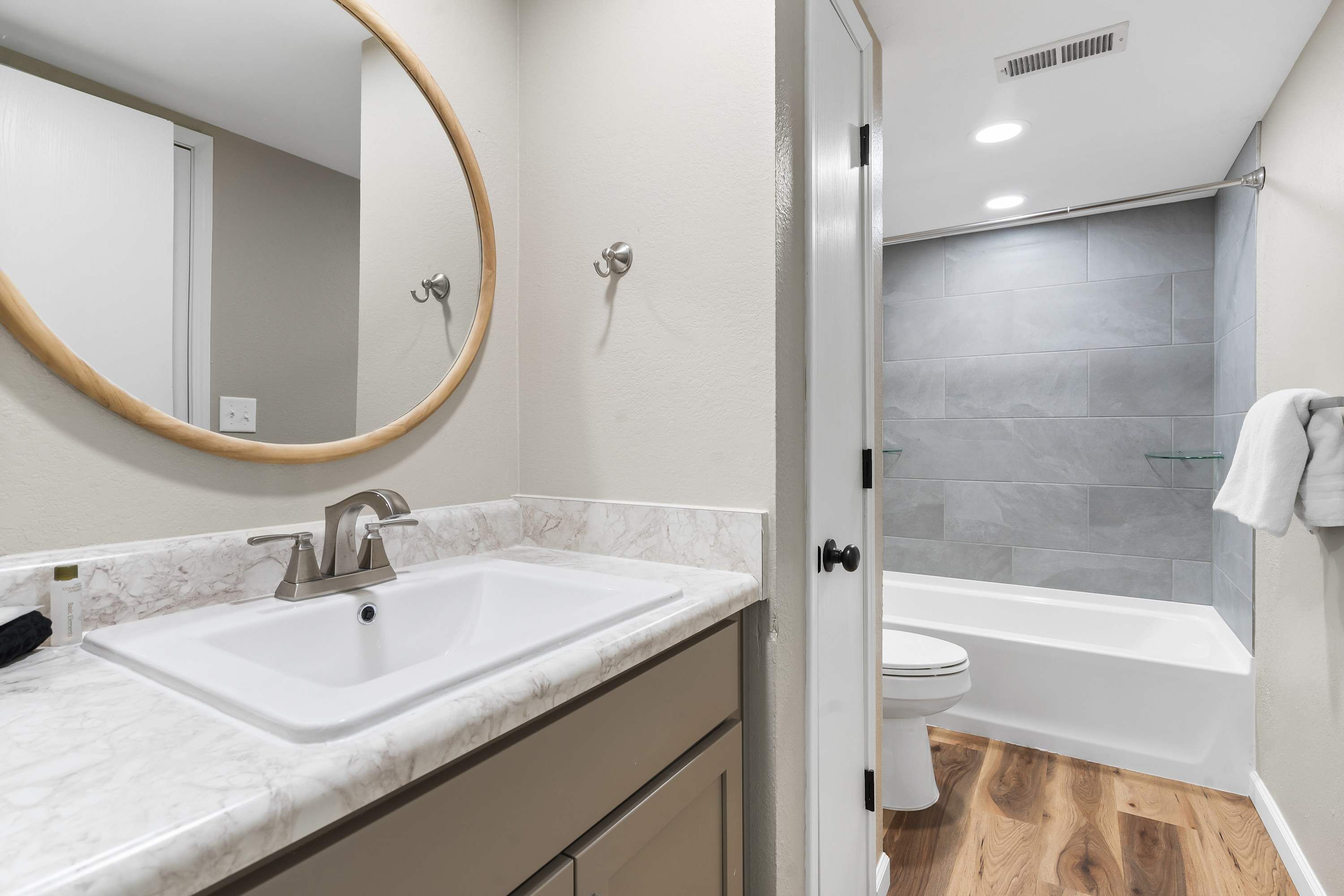 Un baño con lavamanos blanco, un espejo, inodoro y bañera.
