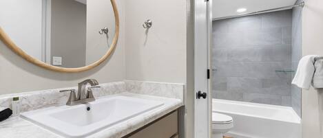Un baño con lavamanos blanco, un espejo, inodoro y bañera.