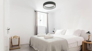 A modern hotel room with a large bed, a bedside table with a lamp, and a view of the outdoors through a window with curtains. - Athens Residence A1 - Cozy Nest near Acropolis (Athina)