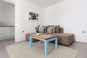 Ein modernes Wohnzimmer mit einem braunen Sofa, einem blauen Couchtisch und einem gemusterten Teppich.