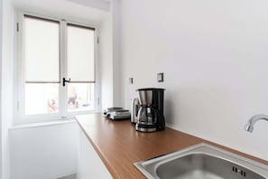 Eine Küche mit Holzarbeitsplatte, einer Kaffeemaschine, einem Wasserkocher und einem Edelstahlspülbecken.