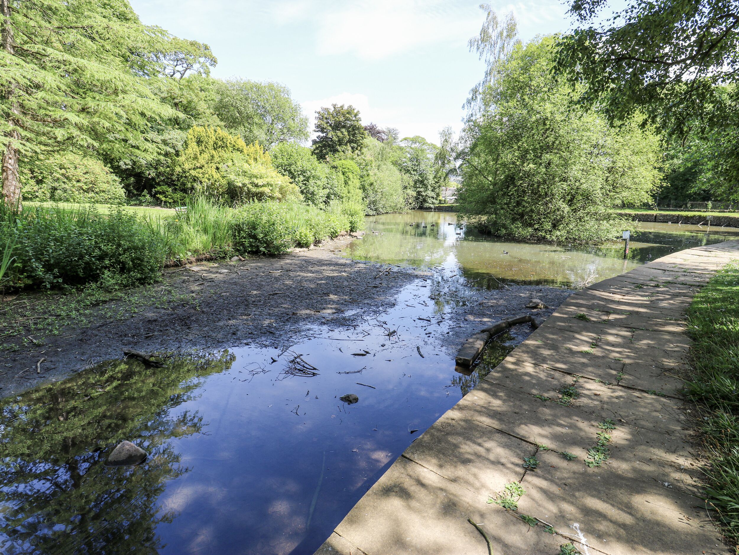 Une rivière paisible, bordée d’une promenade en béton.