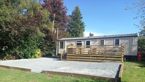 A mobile home with a fenced outdoor area and a gravel driveway. - Emma 6 (Menai Bridge)