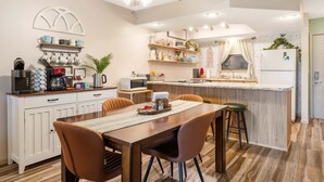 A modern kitchen with a dining area, wooden cabinets, a ceiling fan, and a built-in island with bar stools. - Mossy Pines of the Ozarks (Branson)