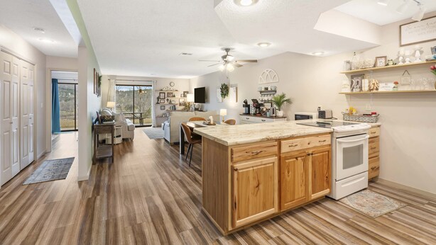 A spacious kitchen with wooden cabinets, a central island, and a built-in oven. - Mossy Pines of the Ozarks (Branson)