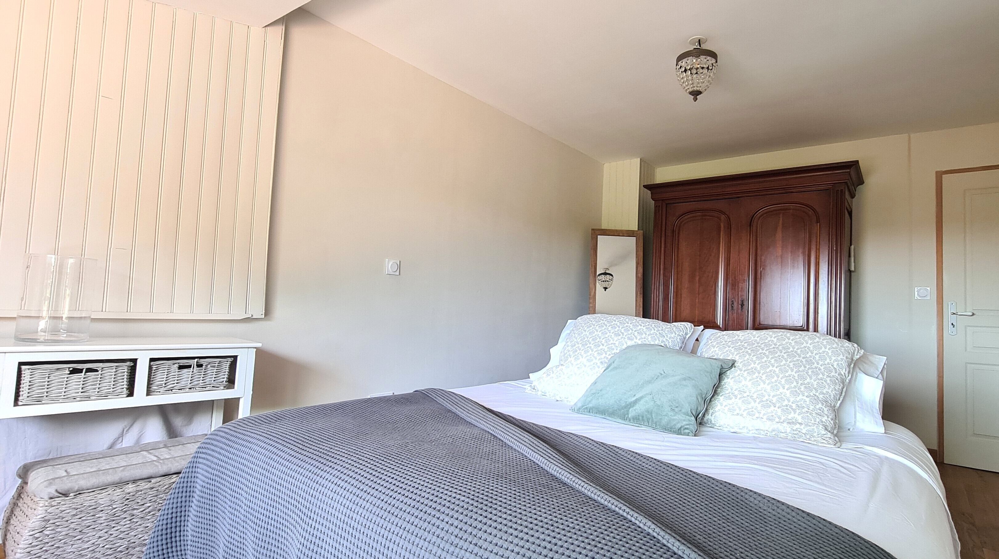A bedroom with a bed, bedside tables, a wardrobe, and a chandelier.