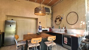 Una cocina compacta con una mesa de comedor de madera, cuatro sillas, un refrigerador, un fregadero y una estufa.