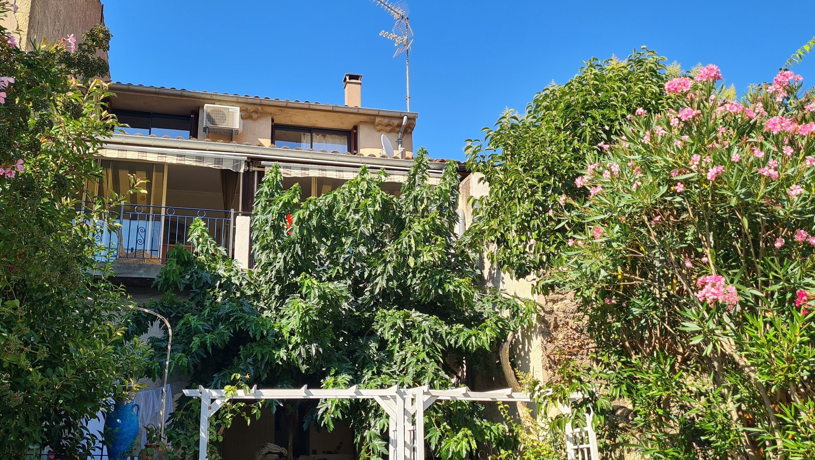 Un edificio con balcón, antenas parabólicas y una pérgola.