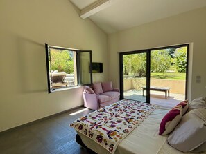 A bedroom with a bed, a pink sofa, and a large window. - La Voile, Beachfront Villa (Grimaud)