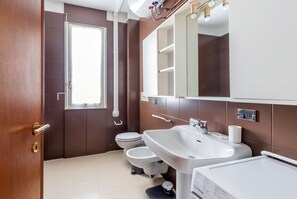 A modern bathroom with a toilet, bidet, sink, and mirror. - Welcoming Flats by Lake Como (Como)