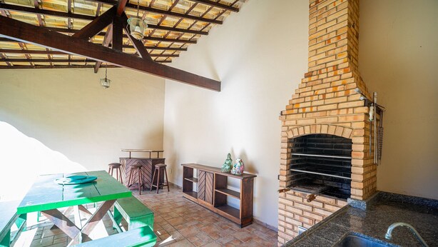 An outdoor patio with a brick oven, a green picnic table, and a bar area. - Cf07 Casa churrasqueira 5 min da praia (Cabo Frio)