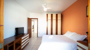 A bedroom with a bed, a TV on a wooden dresser, a ceiling fan, and a wardrobe. - Cf07 Casa churrasqueira 5 min da praia (Cabo Frio)