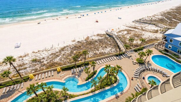 A resort with a beach view, a pool area, and a building with balconies.