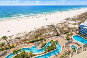 A resort with a beach view, a pool area, and a building with balconies. - Phoenix West 1005 3 Bedroom Condo (Orange Beach)