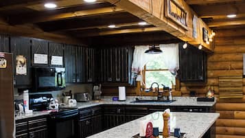 A rustic kitchen with wooden cabinets, a large island, and a refrigerator.