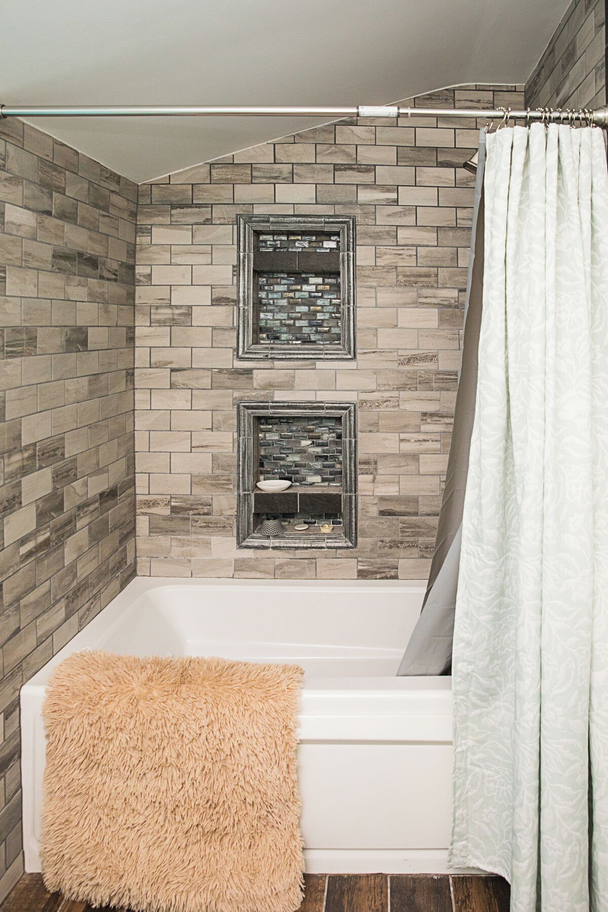 A bathroom with a bathtub, two tiled niches, and a shower curtain.