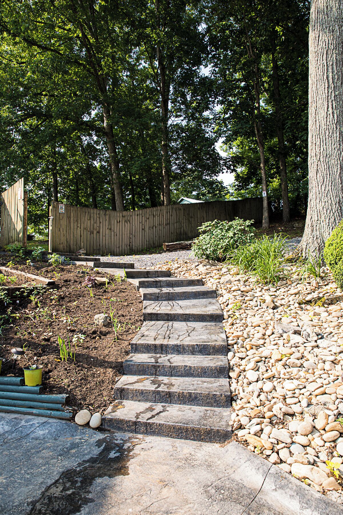A stone staircase leading up to a wooden deck surrounded by trees and a wooden fence.