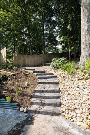 A stone staircase leading up to a wooden deck surrounded by trees and a wooden fence. - Cozy Cabin, Leaves 🍁 Private Swim Jacuzzi Spa- Beautiful Gardens & Orchard   (Jonesborough)