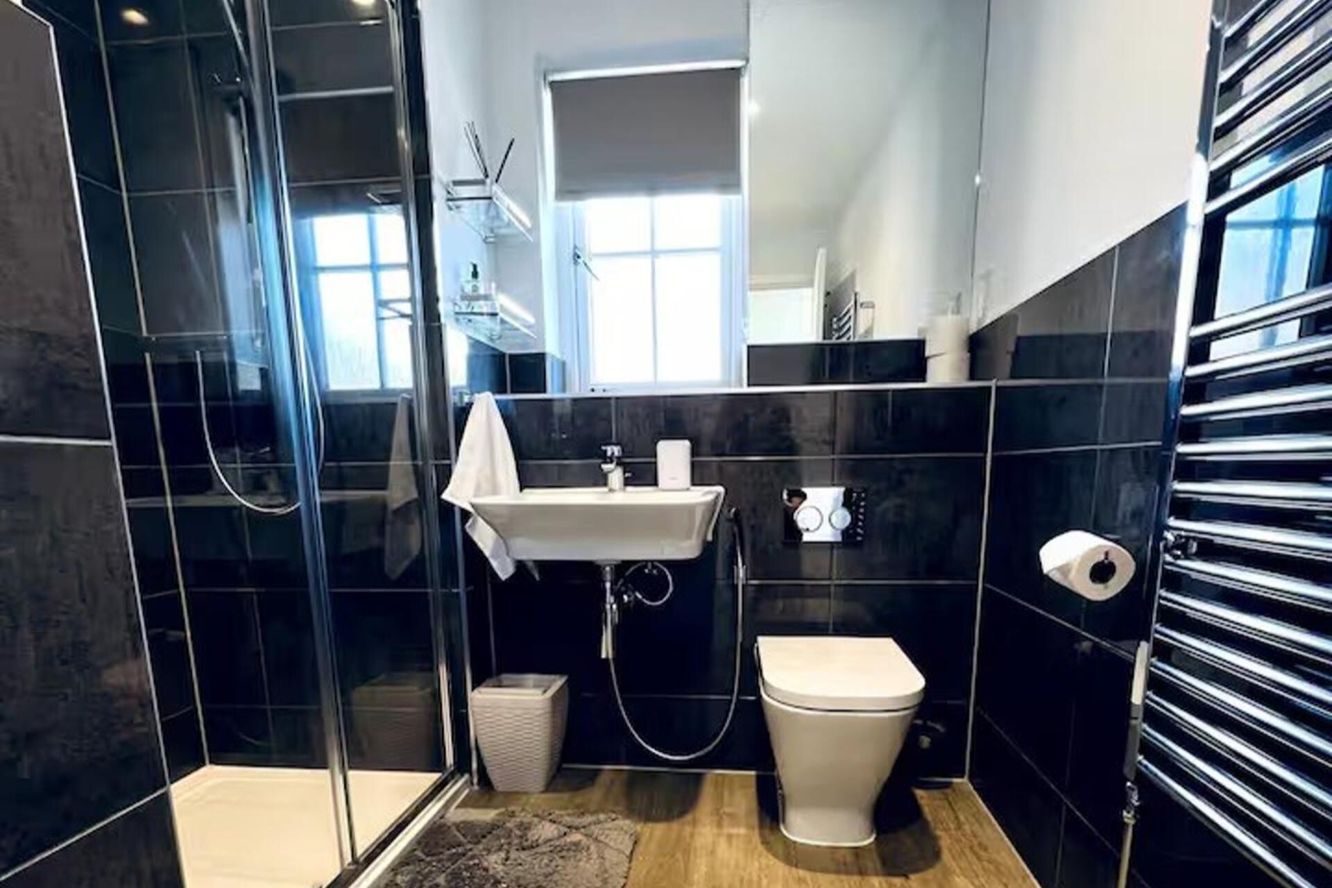 A modern bathroom with a glass shower enclosure, a sink, and a toilet.