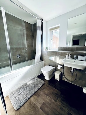 Une salle de bain moderne avec une douche à parois de verre, des toilettes blanches, un lavabo et un miroir.