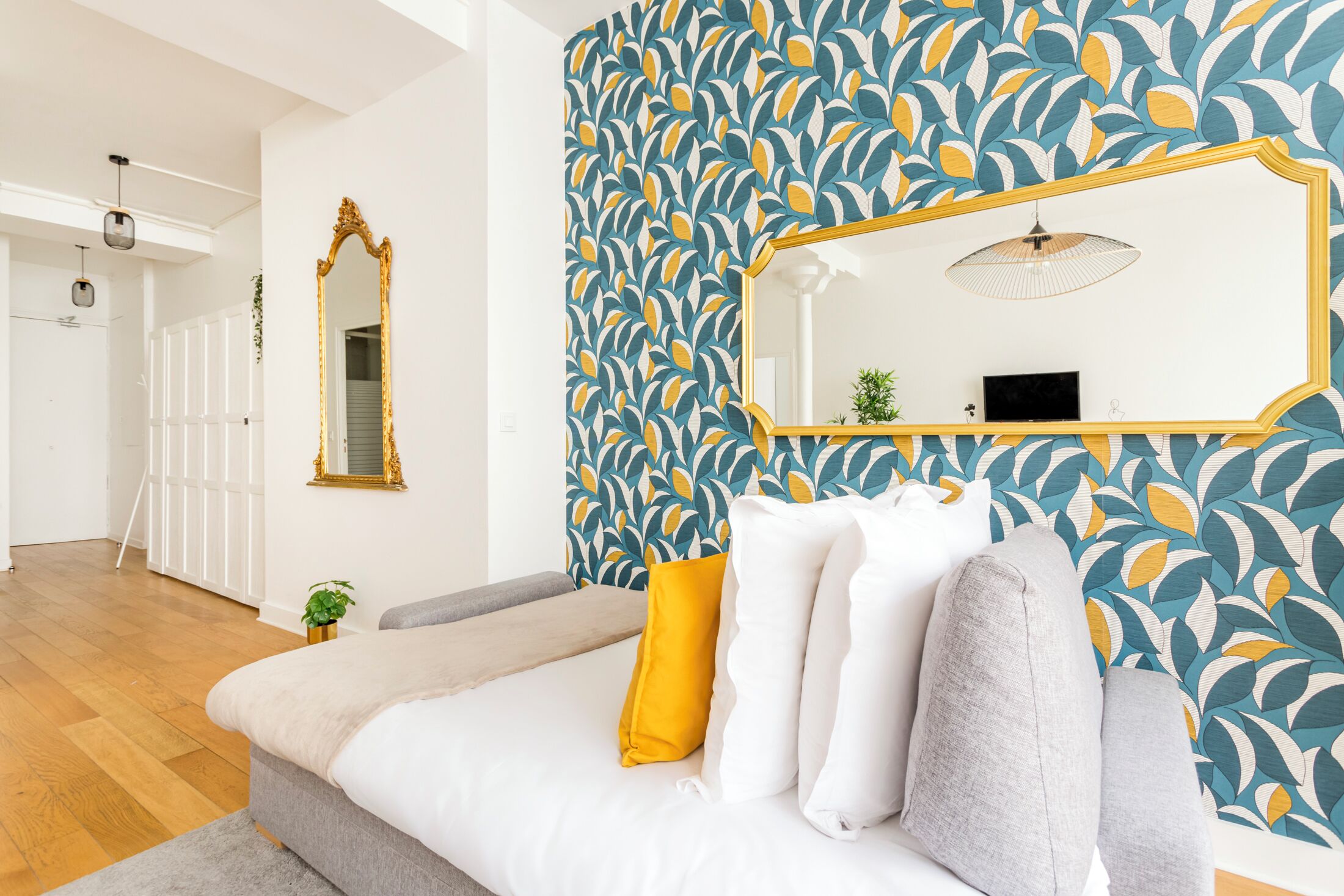 A modern bedroom with a large bed, a mirror, and a patterned wall.
