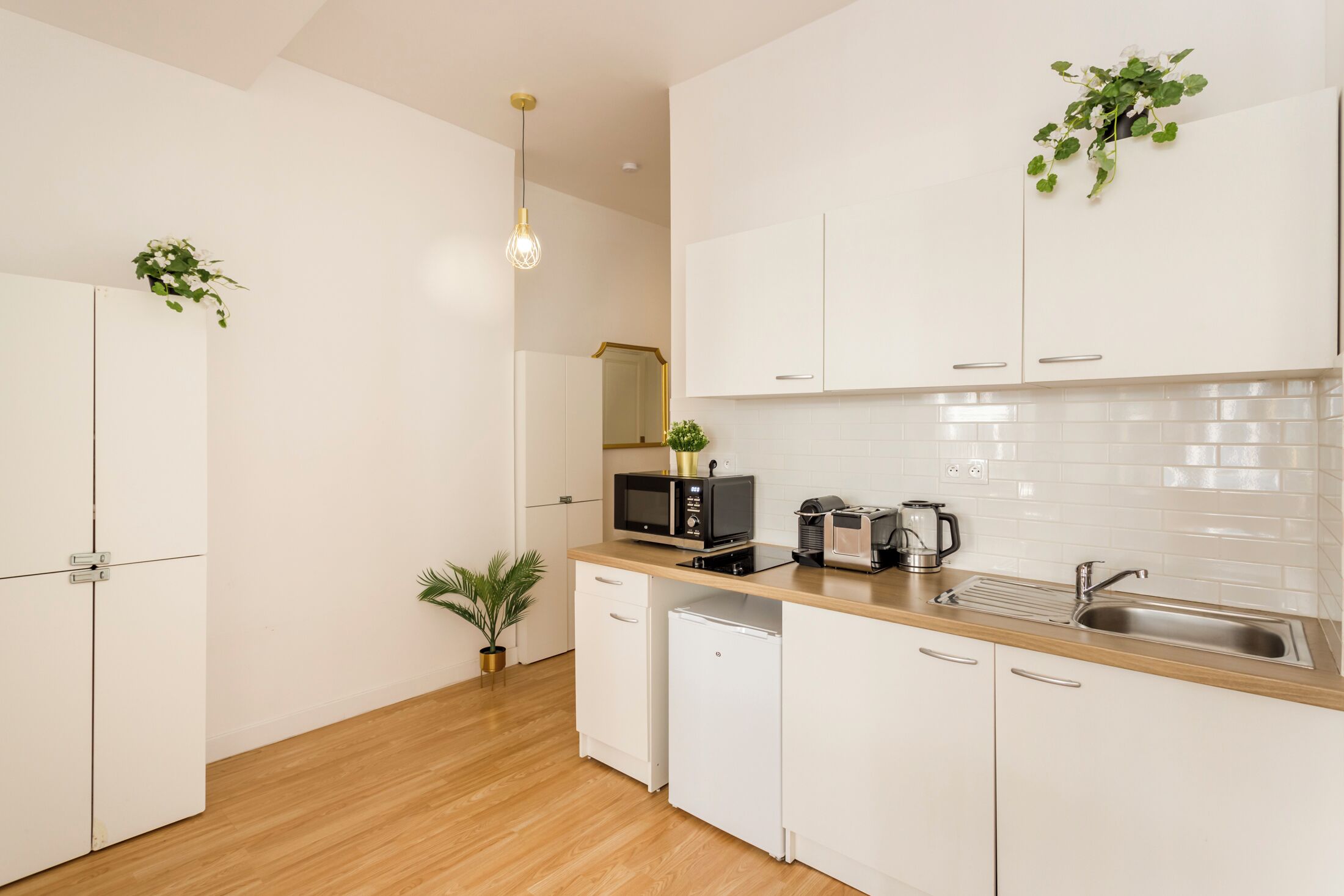 Een moderne keuken met witte kasten, een magnetron, een koffiezetapparaat en een spoelbak.