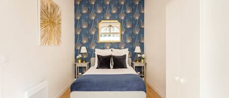 Quarto com cama, mesas de cabeceira, um espelho e uma parede com padrão decorativo.