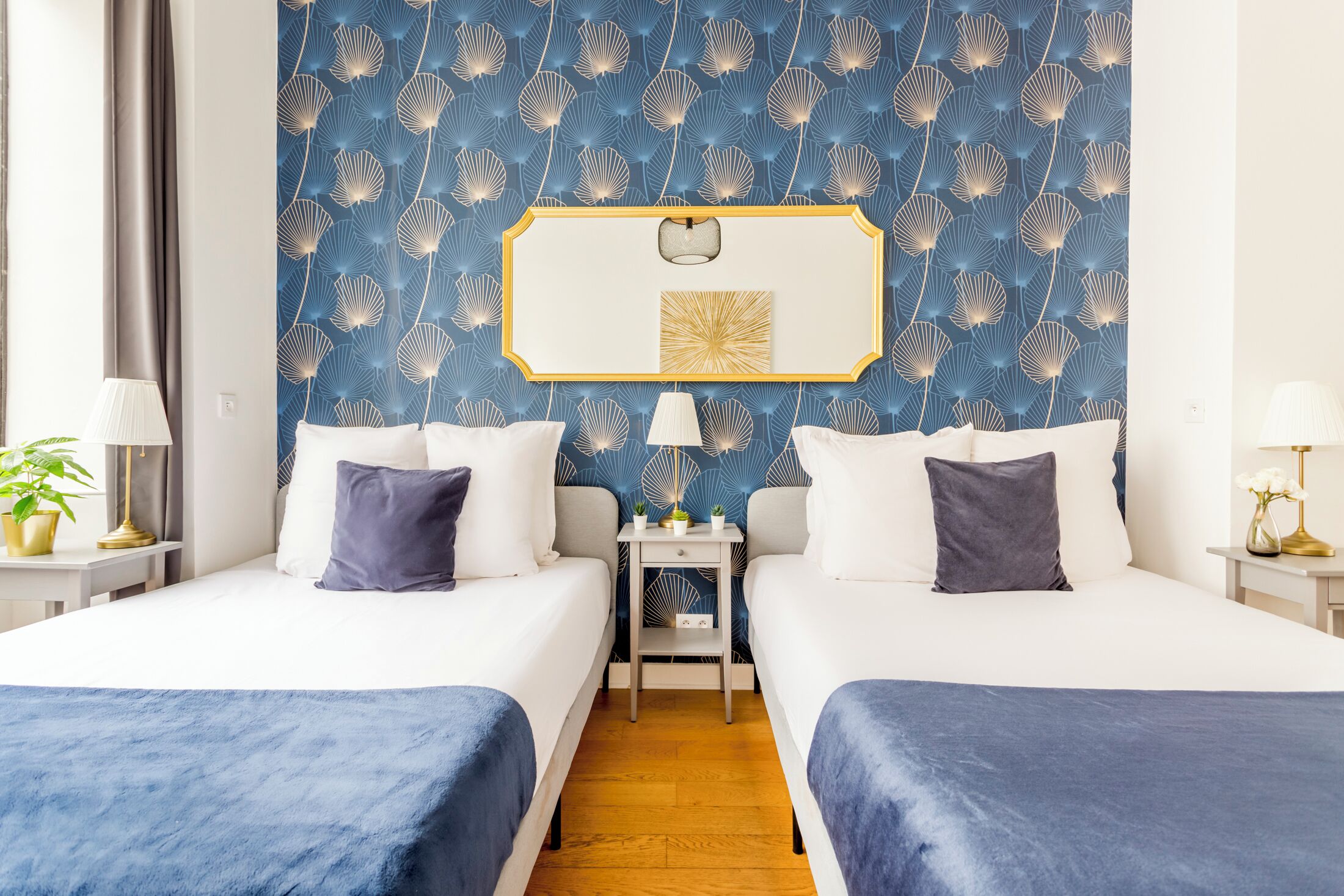 A hotel room with two beds, a nightstand, a mirror, and a wall with a shell pattern.