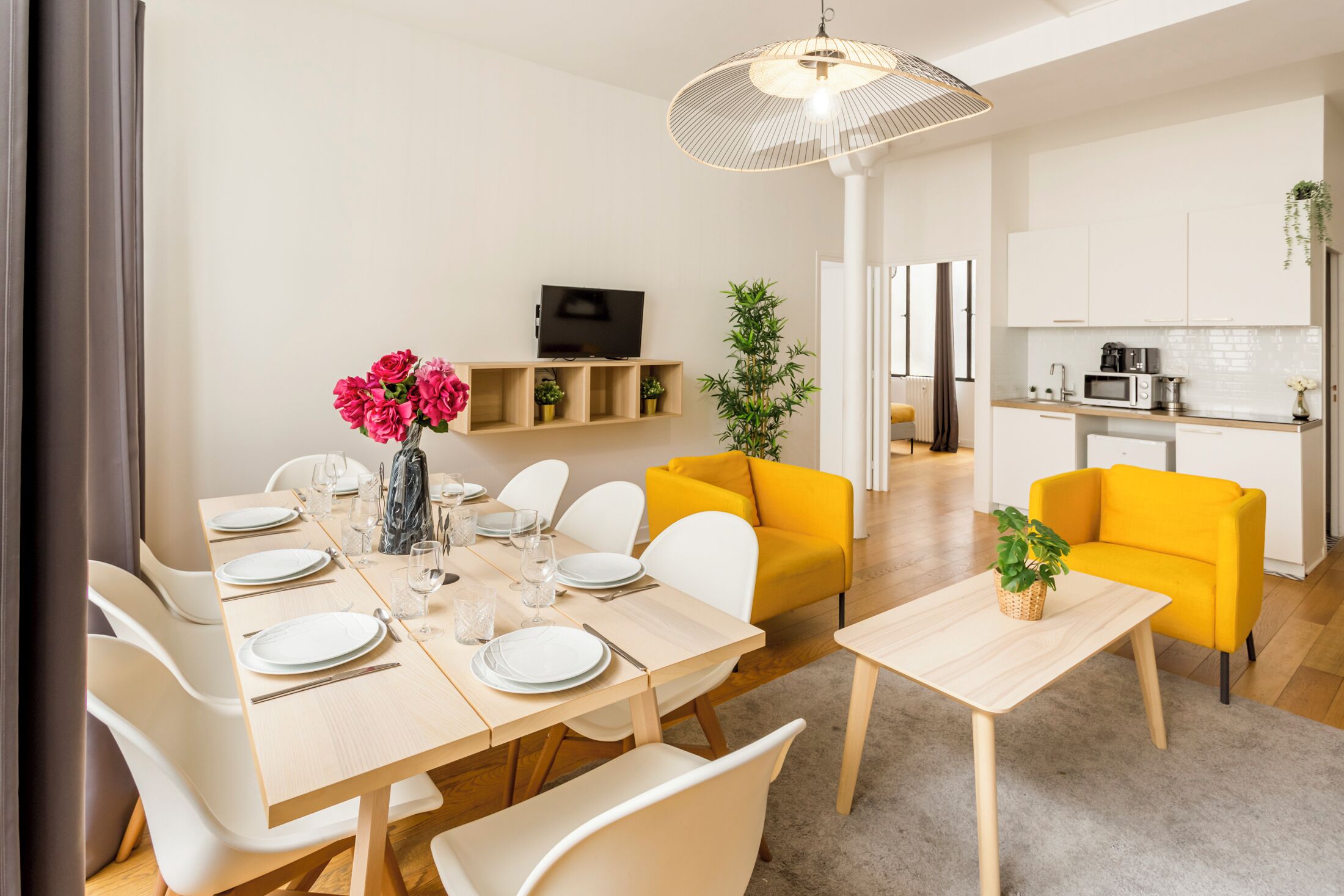 Una sala de estar moderna con comedor, cocina y un sofá amarillo brillante.