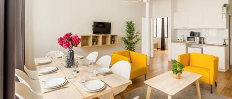 Una sala de estar moderna con comedor, cocina y un sofá amarillo brillante.