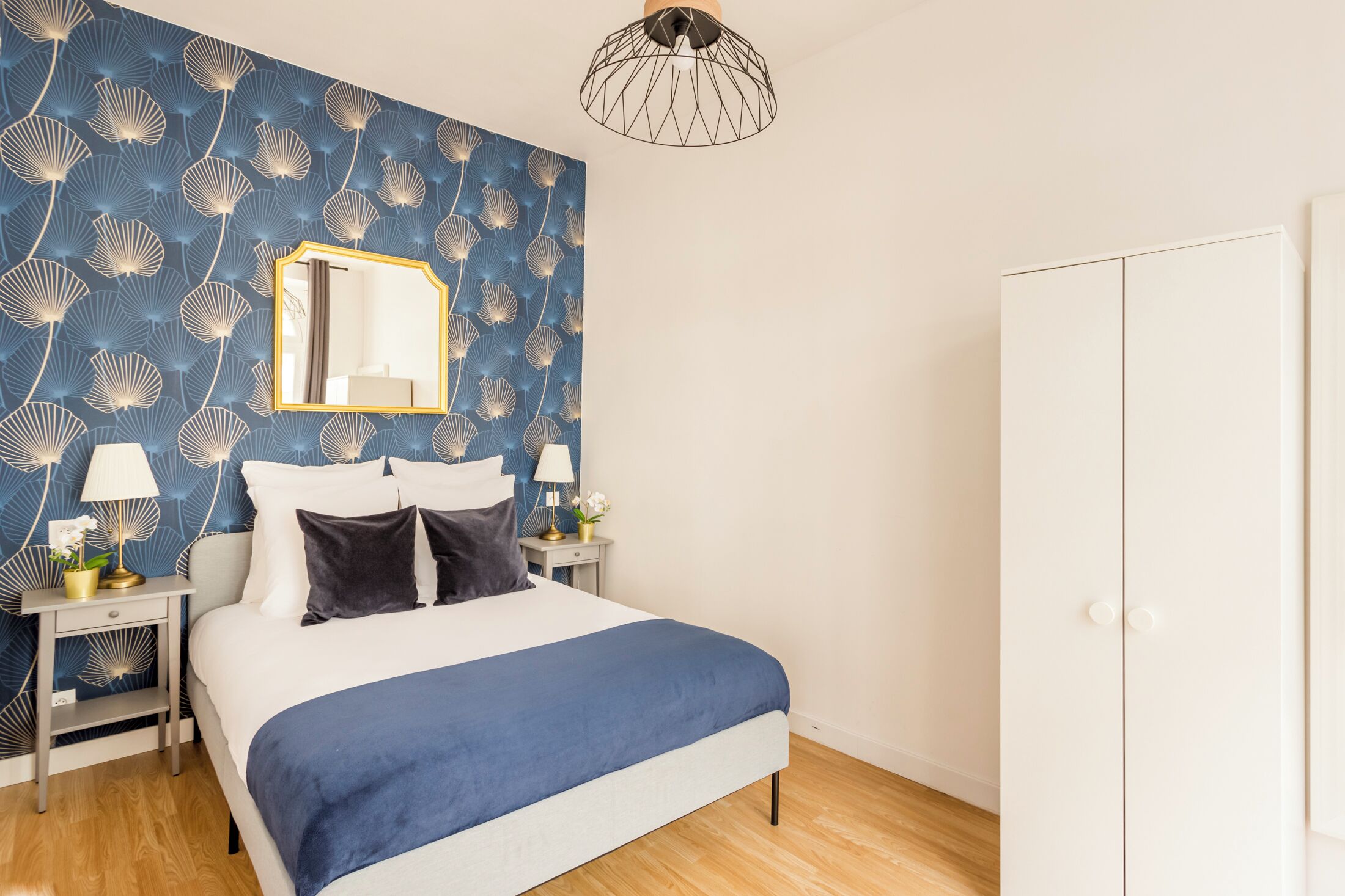 Une chambre à coucher comprenant un lit, des tables de chevet, un miroir et une armoire.