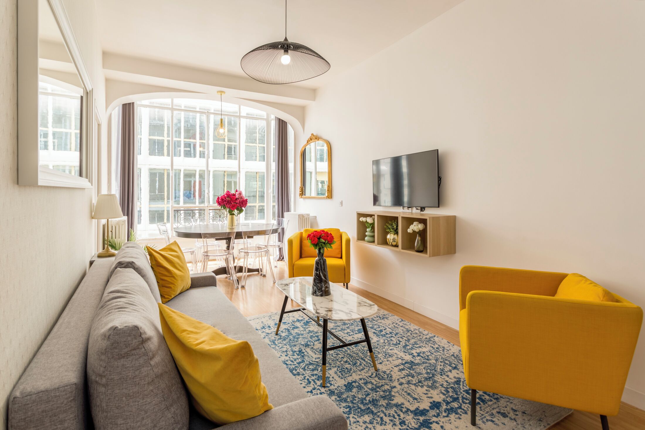 A modern living room with a sofa, yellow armchairs, a coffee table, and a TV.